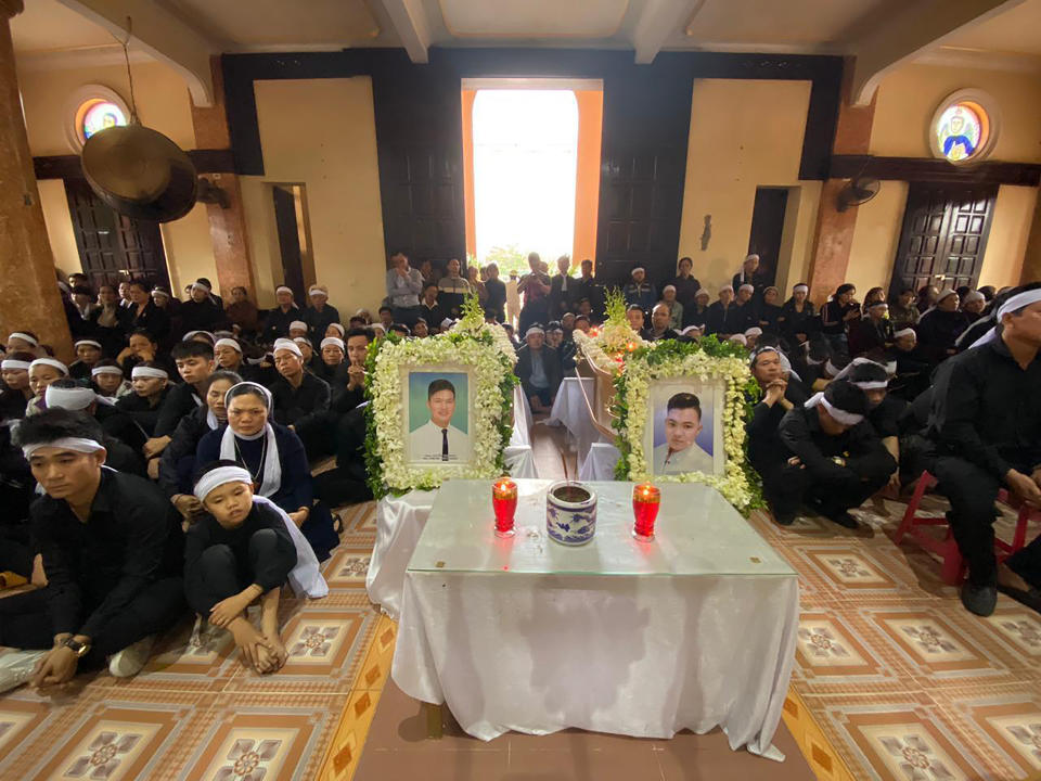 Relatives gather around the coffins of cousins Hoang Van Tiep and Nguyen Van Hung during a funeral ceremony in Trung Song church before their burial on Thursday, Nov. 28, 2019, in Dien Chau, Vietnam. Both Tiep and Hung were among the 39 Vietnamese who died when human traffickers carried them by truck to England in October, and whose remains were among the 16 repatriated to their homeland Wednesday. (AP Photo/Hau Dinh)