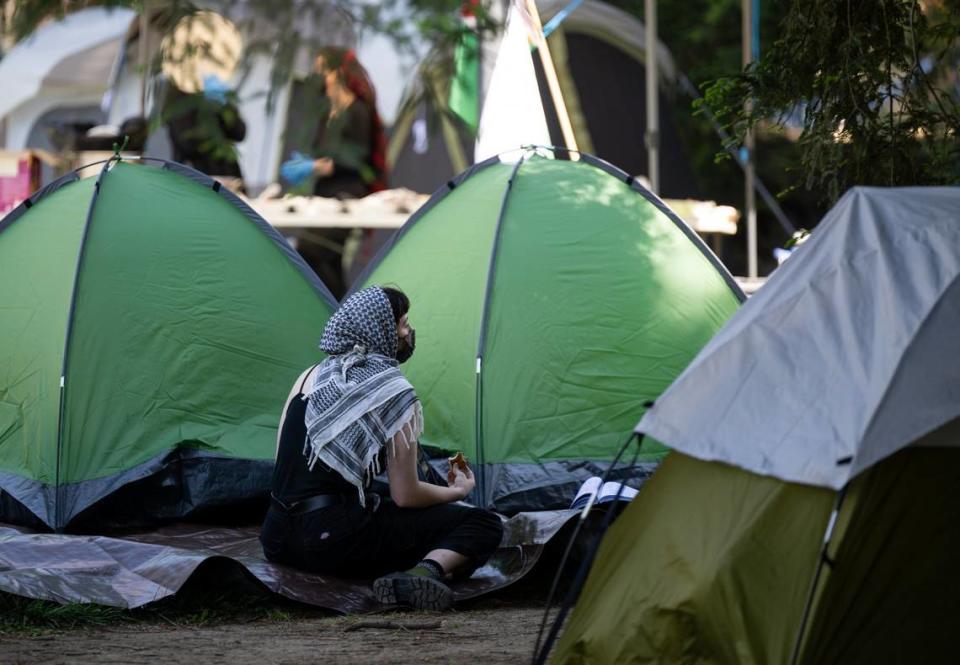 A pro-Palestinian protester sits among tents at an encampment on the UC Davis quad on Monday.