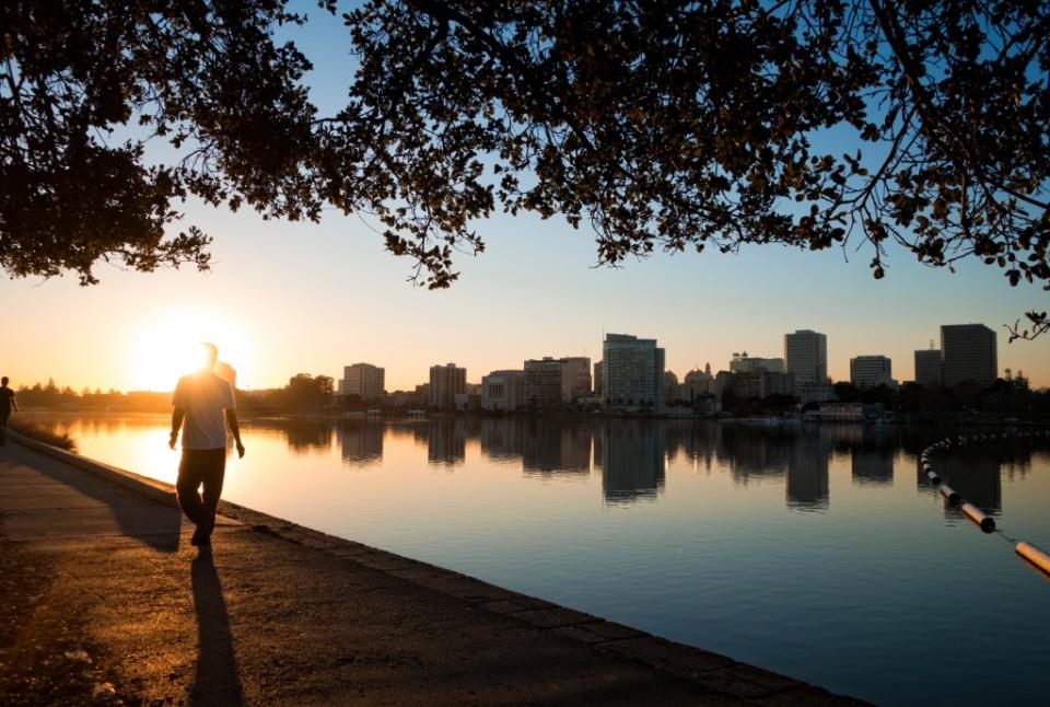 Man walking along Lake Merritt at sunset via Getty Images