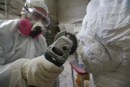 Chinese artist Li Hongbo polishes the nose bridge of a paper sculpture at his studio on the outskirts of Beijing, January 20, 2014. REUTERS/Jason Lee