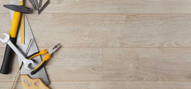 A wooden floor with various tools laid out upon it.