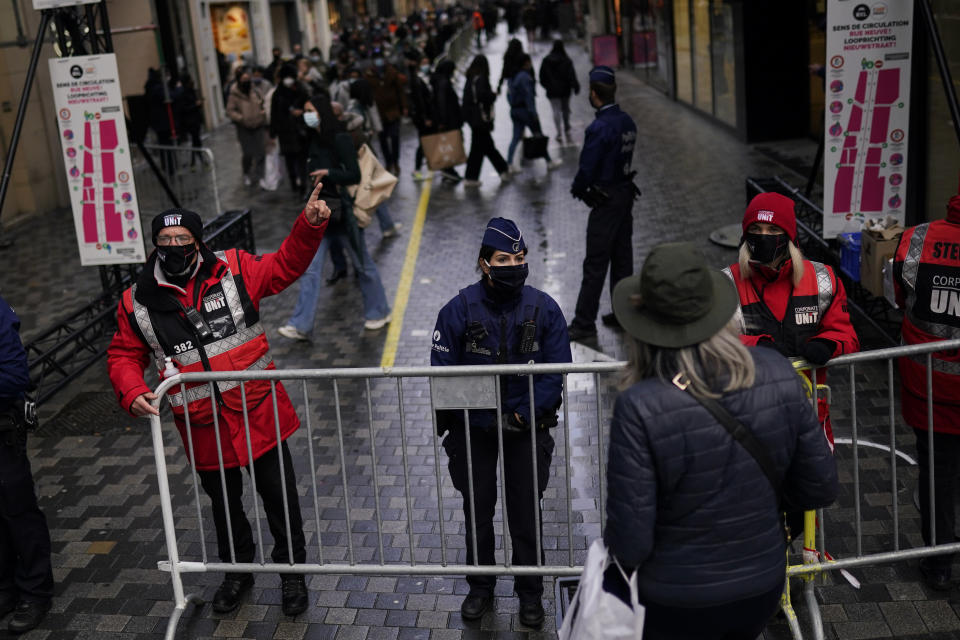 Belgium police officers and security personnel, wearing face mask to prevent the spread of the coronavirus, block temporary an entrance of a commercial street to avoid crowds in downtown Brussels, Tuesday, Dec. 1, 2020. Non-essential shops in Belgium are reopening on Tuesday in the wake of encouraging figures about declining infection rates and hospital admissions because of the coronavirus. (AP Photo/Francisco Seco)