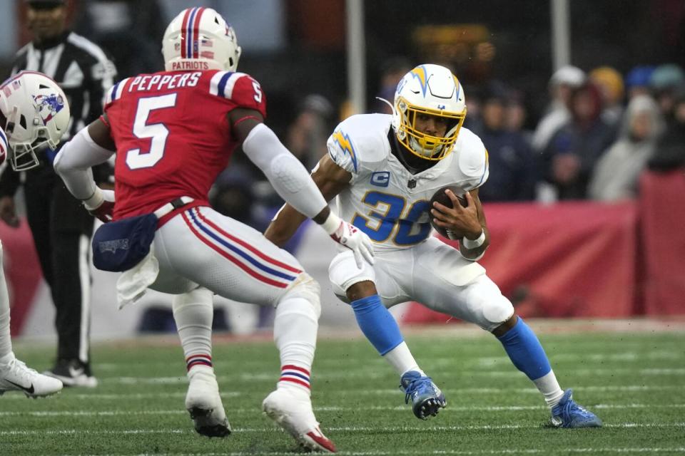 Chargers running back Austin Ekeler tries to elude Patriots safety Jabrill Peppers.