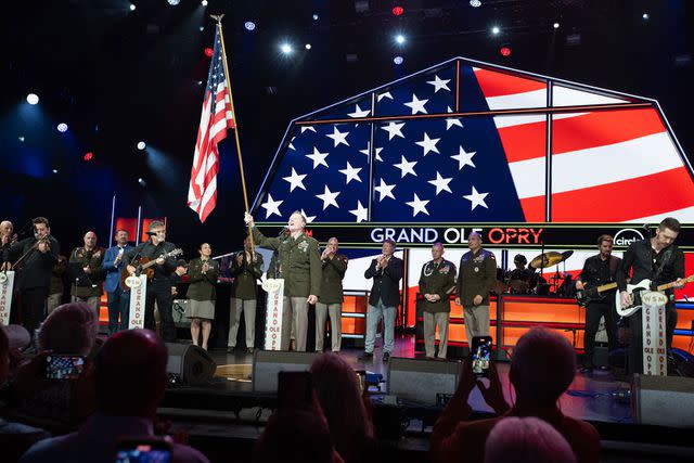 <p>Chris Hollo</p> Staff Sergeant and Warrant Officer candidate Craig Morgan (center, holding U.S. flag) performs "Soldier" after being sworn into the U.S. Army Reserve during the Grand Ole Opry's live show on July 29, 2023