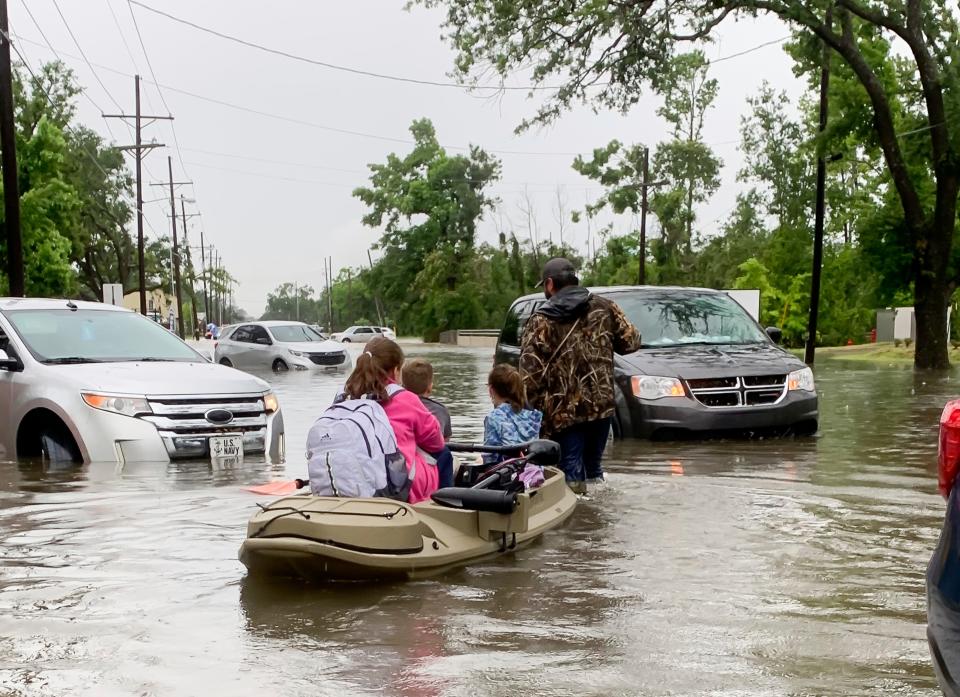 Parents use boats to pick up students from schools after nearly a foot of rain fell in Lake Charles, La., on May 17, 2021.