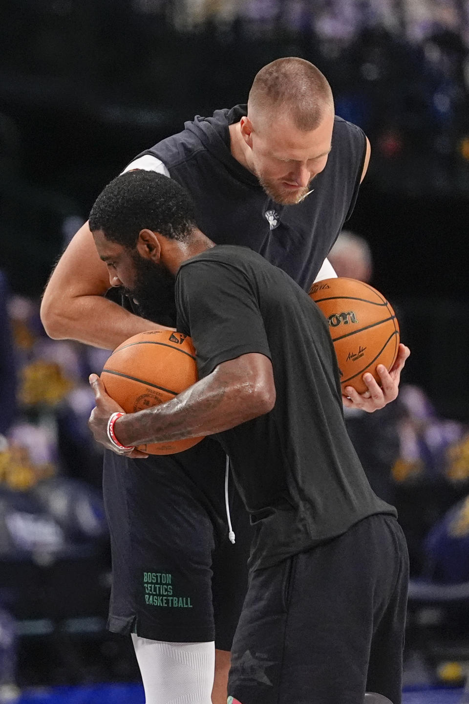 Boston Celtics center Kristaps Porzingis, top, greets Dallas Mavericks guard Kyrie Irving prior to Game 4 of the NBA basketball finals, Friday, June 14, 2024, in Dallas. (STF Photo/Julio Cortez)