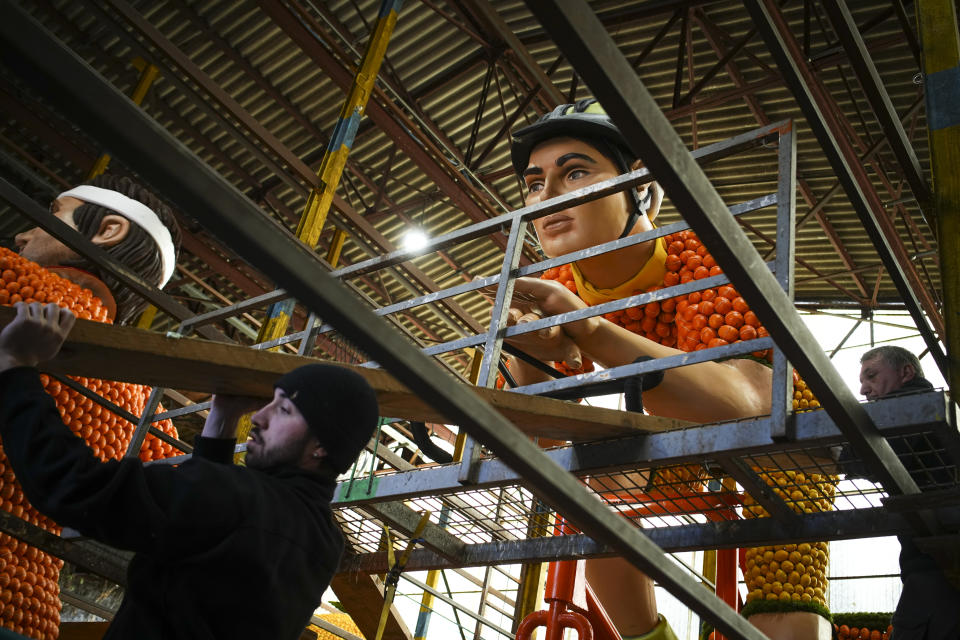 Workers prepare an olympic cyclist sculpture at a warehouse during the 90th Olympia in Menton edition of the Lemon Festival in Menton, southern France, Saturday, Feb. 17, 2024. (AP Photo/Daniel Cole)