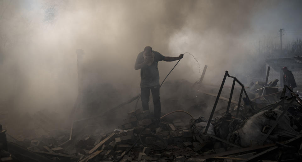 Neighbours try to extinguish the fire of a house, destroyed after a Russian attack in Kharkiv, Ukraine.