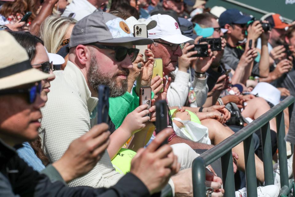 Tennis fans watch and record as Carlos Alcarez and Frances Tiafoe practice on a packed Stadium 9 court during the BNP Paribas Open in Indian Wells, Calif., March 8, 2023. 