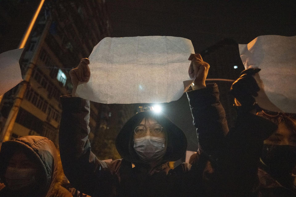 Protesters hold up blank pieces of paper and chant slogans as they march to protest strict anti-virus measures in Beijing, Nov. 27, 2022. Thousands of people demonstrated across China in what came to be called the White Paper movement, after the blank sheets of paper protesters used to represent the country's strict censorship controls. One year later, China has all but forgotten the protests. The state reacted quickly, breaking up the marches with arrests and threats and ending COVID-19 controls. (AP Photo/Ng Han Guan)