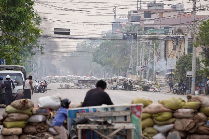 Protesters take cover behind barricades during a demonstration against the military coup in Mandalay