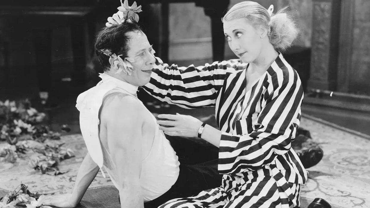 A young Bert Lahr smiling at a woman wearing a striped suit.