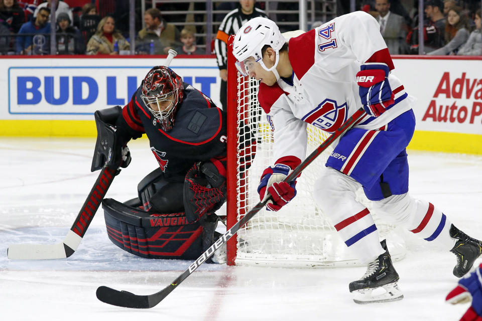 Montreal Canadiens' Nick Suzuki (14) moves the puck around the net to challenge Carolina Hurricanes goaltender Petr Mrazek (34), of Czech Republic, during the first period of an NHL hockey game in Raleigh, N.C., Tuesday, Dec. 31, 2019. (AP Photo/Karl B DeBlaker)