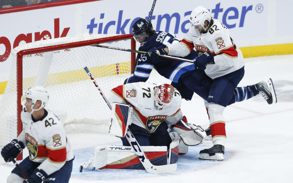 Winnipeg Jets' Mark Scheifele (55) crashes into Florida Panthers goaltender Sergei Bobrovsky (72) as Panthers' Kevin Stenlund (82) defends during third-period NHL hockey game action in Winnipeg, Manitoba, Saturday, Oct. 14, 2023. (John Woods/The Canadian Press via AP)