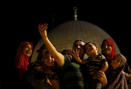 Palestinian Dahud Hamad, 48, from the West Bank city of Hebron, takes a selfie photo with his family in front of the Dome of the Rock on the compound known to Muslims as the Noble Sanctuary and to Jews as Temple Mount, in Jerusalem's Old City, during the holy month of Ramadan, July 1, 2015. REUTERS/Ammar Awad