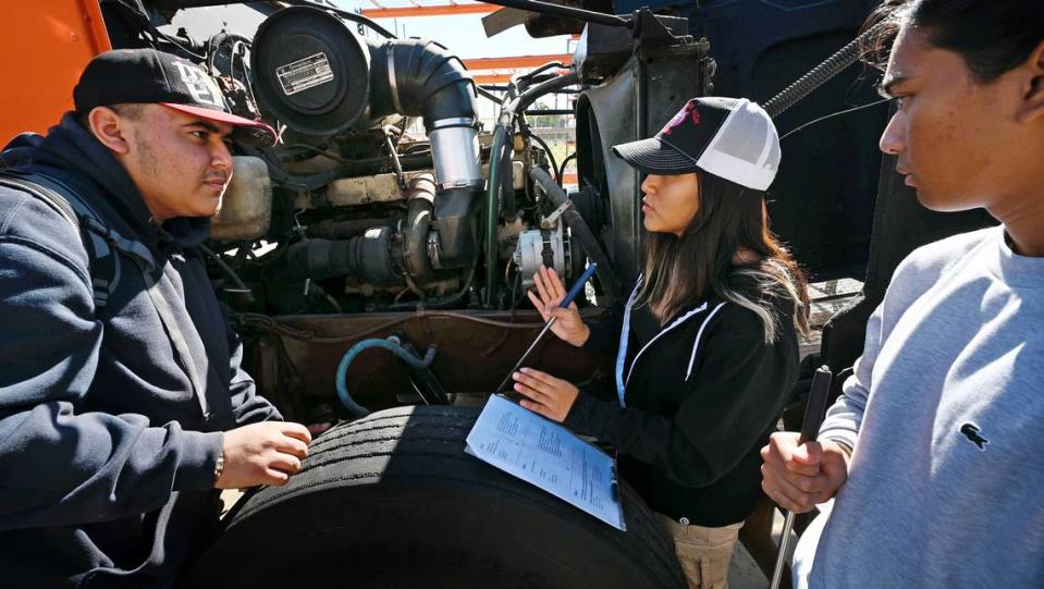 Students Christopher Delgado, left, Teffany Dominguez Santamaria, middle, and Melvino Roxas conduct a pre-trip inspection during trucking class at Patterson High School in Patterson, Calif., Friday, Oct. 27, 2023. The school has career technical education class to teach trucking and help students gain a commercial drivers permit.