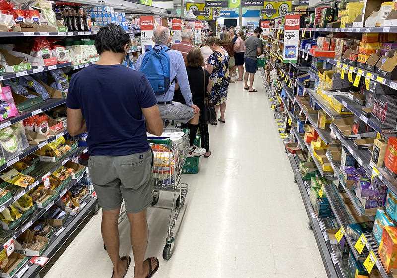 People are seen lined up waiting to go through the checkout inside Woolworths at Mt Gravatt in Brisbane.