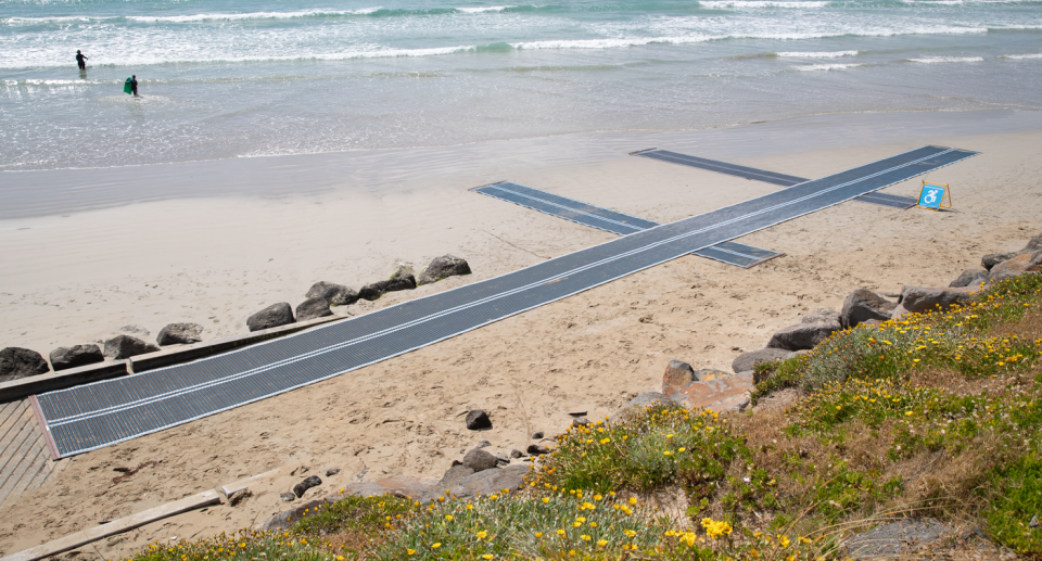 Blue beach matting on the sand from the path to the edge of the ocean.