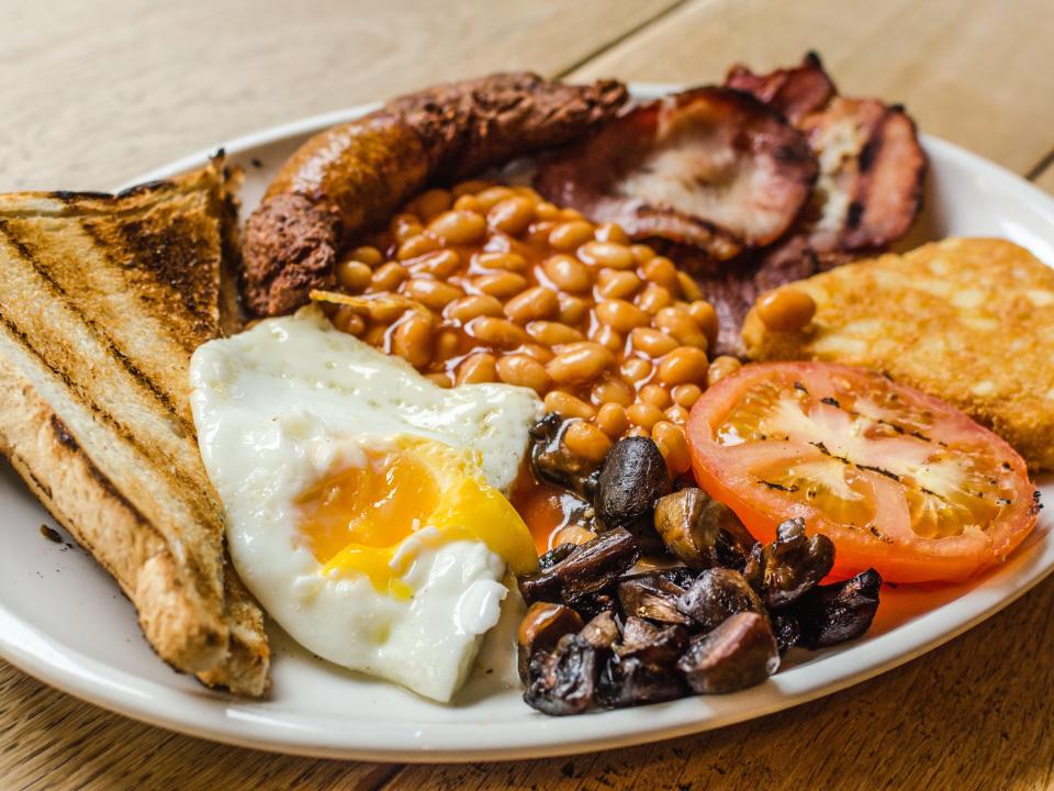 Full English Breakfast including sausages, grilled tomatoes and mushrooms, egg, bacon, baked beans and bread.