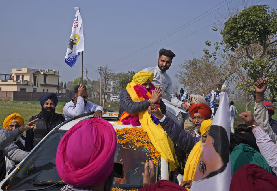 Aam Aadmi Party's candidate Harbhajan Singh from the Jandiala constituency, atop a car, campaigns for assembly elections on the outskirts of Amritsar, in Indian state of Punjab, Tuesday, Feb. 15, 2022. India's Punjab state will cast ballots on Sunday that will reflect whether Indian Prime Minister Narendra Modi's ruling Bharatiya Janata Party has been able to neutralize the resentment of Sikh farmers by repealing the contentious farm laws that led to year-long protests. (AP Photo/Manish Swarup)