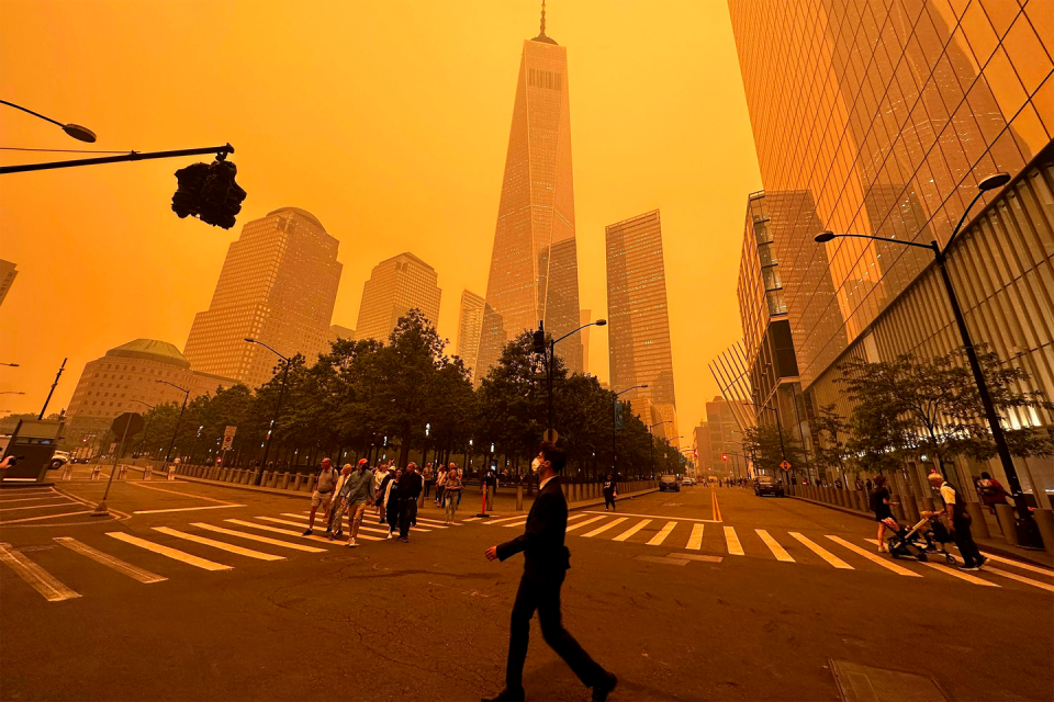 man walking through the financial district nyc with a fask mask on through an orange sky