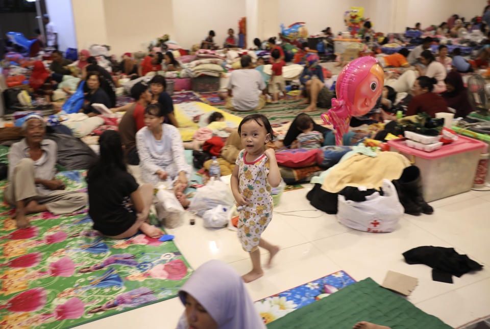 A young girl holds a balloon as people rest at a temporary shelter for those affected by the floods in Jakarta, Indonesia, Friday, Jan. 3, 2020. Severe flooding in the capital as residents celebrated the new year has killed dozens of people and displaced hundreds of thousands others. (AP Photo/Dita Alangkara)