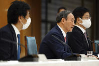 ADDS NAME OF PARTICIPANTS - Japanese Prime Minister Yoshihide Suga, center, announces that Tokyo, Kyoto and Okinawa will be applied for pre-emergency status under a new prevention law during a government task force meeting at the prime minister's office Friday, April 9, 2021, in Tokyo. Japan announced Friday that it will raise the coronavirus alert level in Tokyo to allow tougher measures to curb the rapid spread of a more contagious variant ahead of the Summer Olympics. Minister of Health, Labor and Welfare Norihisa Tamura, is at left, and Japan's Chief Cabinet Secretary Katsunobu Kato, is at right. (AP Photo/Eugene Hoshiko, Pool)