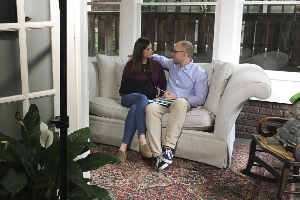 In this Sept. 25, 2018 photo provided by Laura Trujillo, Whitney Austin and husband Waller, right, sit together in their home in Louisville, Ky. Believing she was dying after a gunman riddled her body with bullets, a bank executive said Wednesday, Sept. 26, she urged first responders to save her life for her two small children. Austin survived 12 gunshots Sept. 6. She recounted her ordeal in a taped interview shown Wednesday on ABC's "Good Morning America." (Courtesy Laura Trujillo via AP)