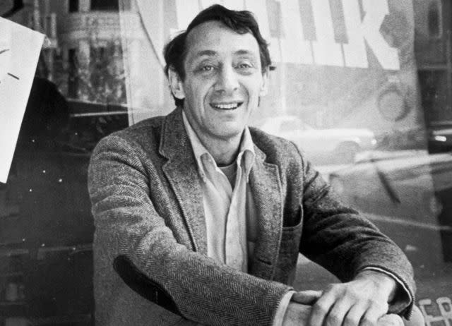 <p>Bettmann</p> Harvey Milk sits outside his camera shop in San Francisco, November 9, 1977.