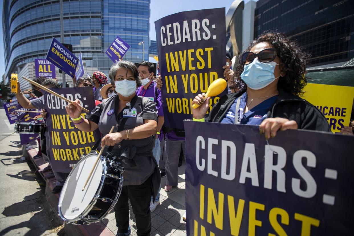 People hold signs during a protest outside a hospital.