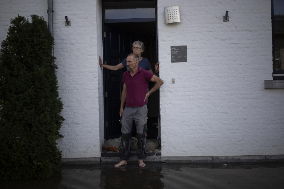 A coupe stands outside their home, in the town of Brommelen, Netherlands, Saturday, July 17, 2021. In the southern Dutch province of Limburg, which also has been hit hard by flooding, troops piled sandbags to strengthen a 1.1-kilometer (0.7 mile) stretch of dike along the Maas River, and police helped evacuate low-lying neighborhoods. (AP Photo/Bram Janssen)