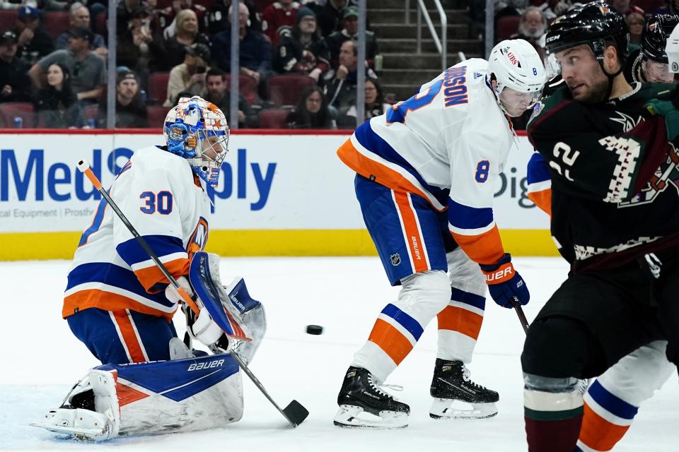 New York Islanders goaltender Ilya Sorokin (30) makes a save as Islanders defenseman Noah Dobson (8) helps out and Arizona Coyotes left wing Johan Larsson (22) looks for the puck during the first period of an NHL hockey game Saturday, Oct. 23, 2021, in Glendale, Ariz. (AP Photo/Ross D. Franklin)