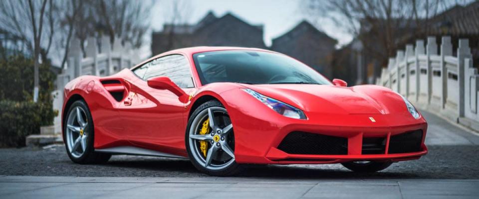 A red Ferrari 488 GTB parked in front of a stone bridge.