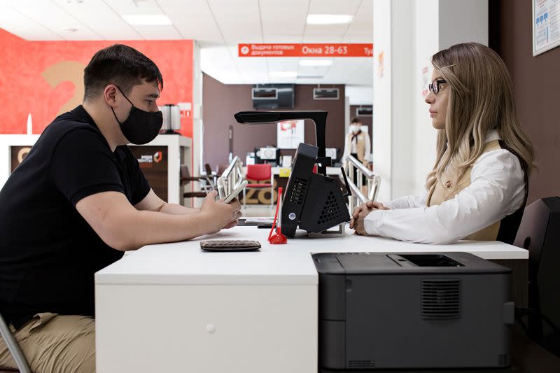 A female human-like robot assists a visitor at a document processing centre in Perm