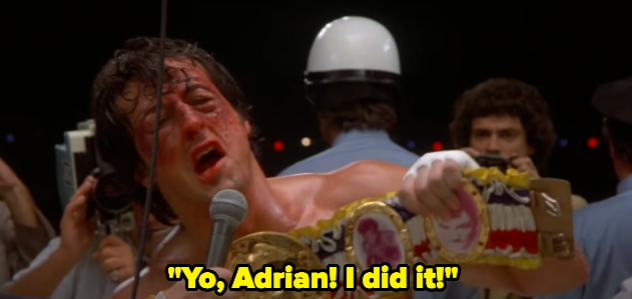 A man holds up a boxing belt and yells "Yo Adrian! I did it!"