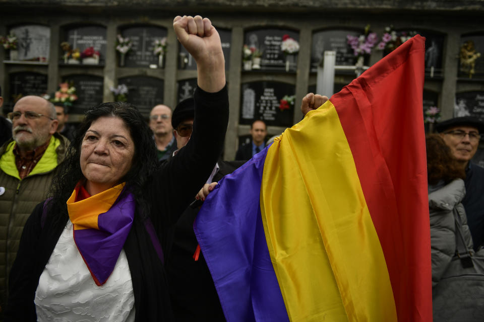 A woman holds up her left fist beside to a Spanish Republican flag during a tribute 46 unidentified people killed during the Spanish Civil War, at San Jose cemetery, Pamplona, northern Spain, Monday, April 1, 2019. Marking eight decades since the end of the Spanish Civil War, the remains of 46 unidentified victims of the conflict have been reburied in the northern city of Pamplona. More than half a million people died in the 1936-1939 war between rebel nationalist forces led by Gen. Francisco Franco and defenders of the short-lived Spanish republic. (AP Photo/Alvaro Barrientos)