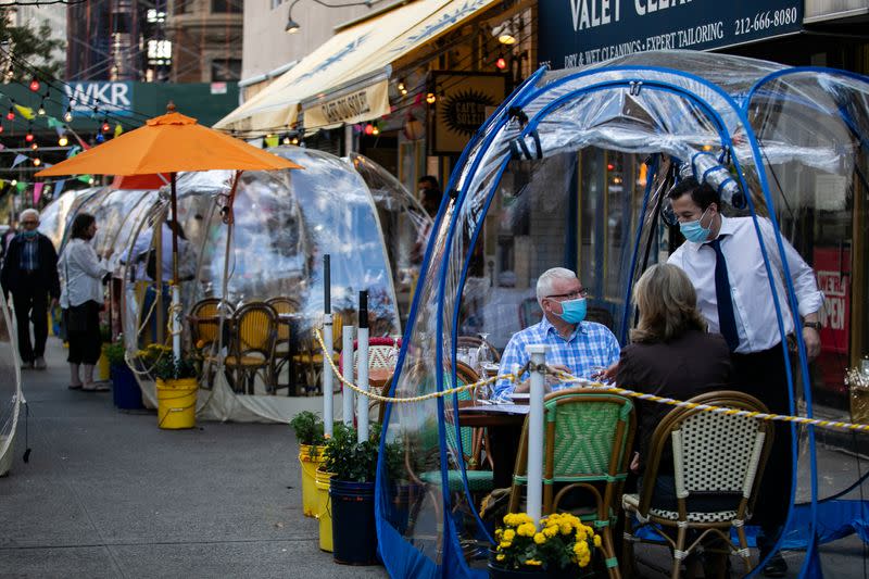 People sit outside Cafe Du Soliel under bubble tents