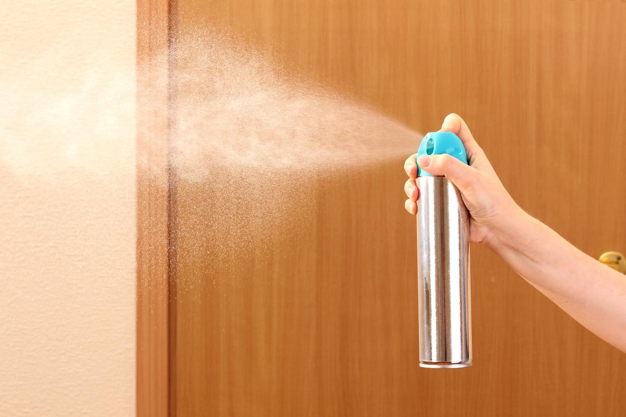 sprayed air freshener in hand on room