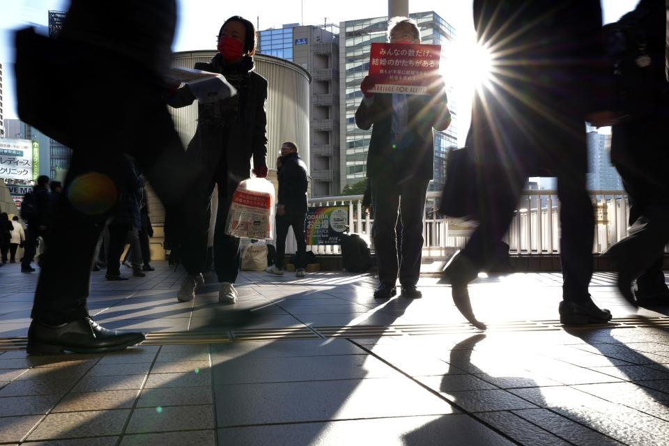 LGBTQ activists distribute chocolates to morning commuters at Shinagawa Station, marking the fifth anniversary of the day a group of plaintiffs launched their legal battle to achieve the marriage equality, to bolster the momentum toward pushing the government to provide the protection Wednesday, Feb. 14, 2024, in Tokyo. A banner reads as "Everyone has their own way of getting married." (AP Photo/Eugene Hoshiko)