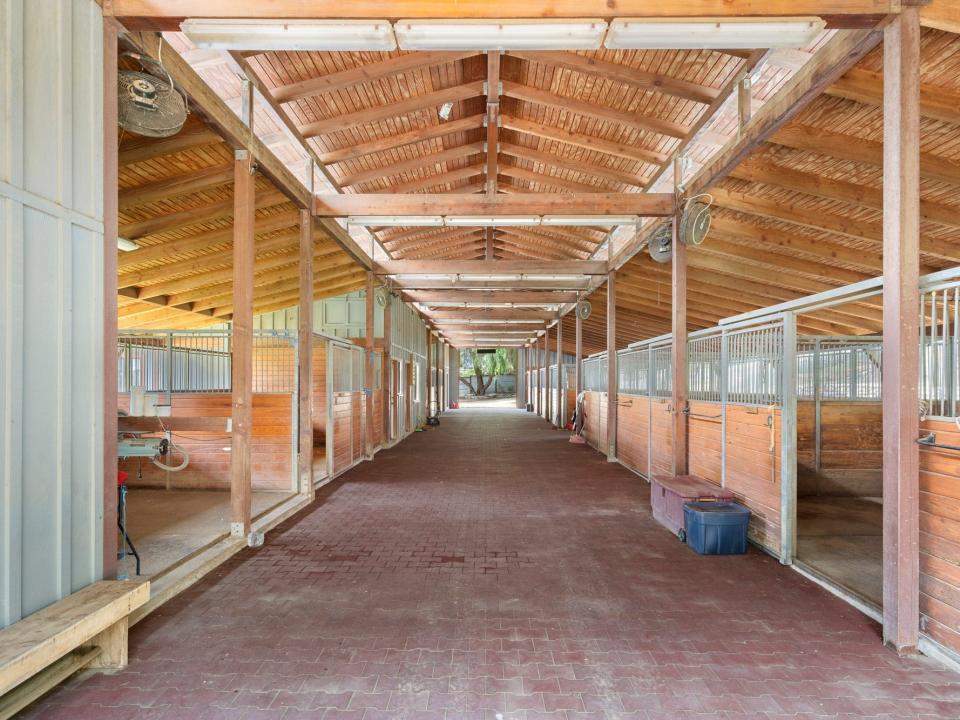 A wooden building with a large hall and horse pens at the sides
