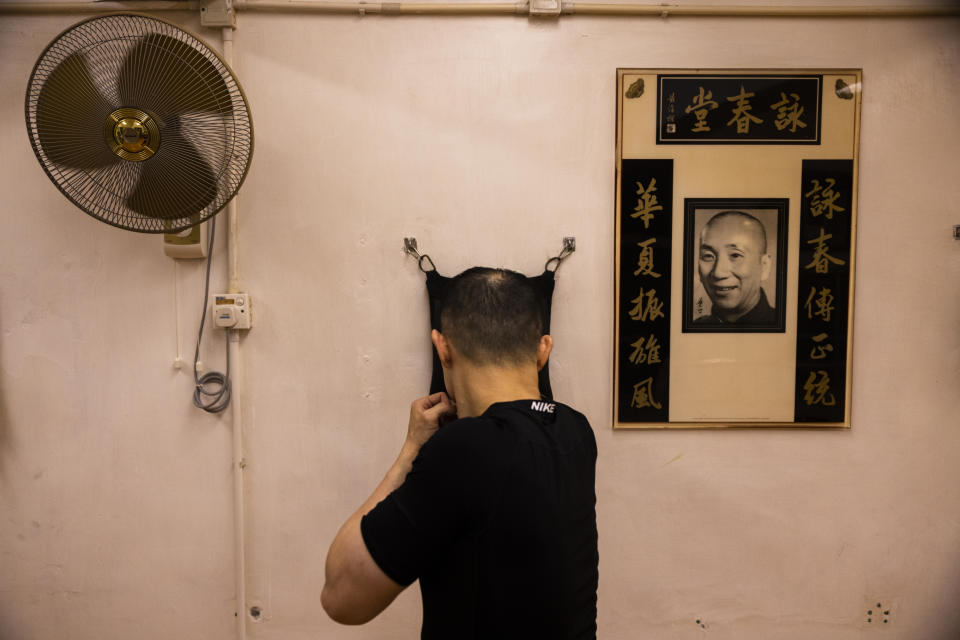 Sifu Ricky Fong practices a punching bag in front of a photo of grandmaster Ip Man during a Jeet Kune Do class in Hong Kong, Wednesday, July 19, 2023. (AP Photo/Louise Delmotte)