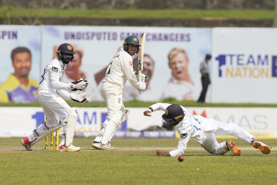 Australia's Usman Khawaja watches his shot as Sri Lanka's Pathum Nissanka attempts to field the ball infant of Niroshan Dickwella during the day two of the first test cricket match between Australia and Sri Lanka in Galle, Sri Lanka, Thursday, June 30, 2022. (AP Photo/Eranga Jayawardena)