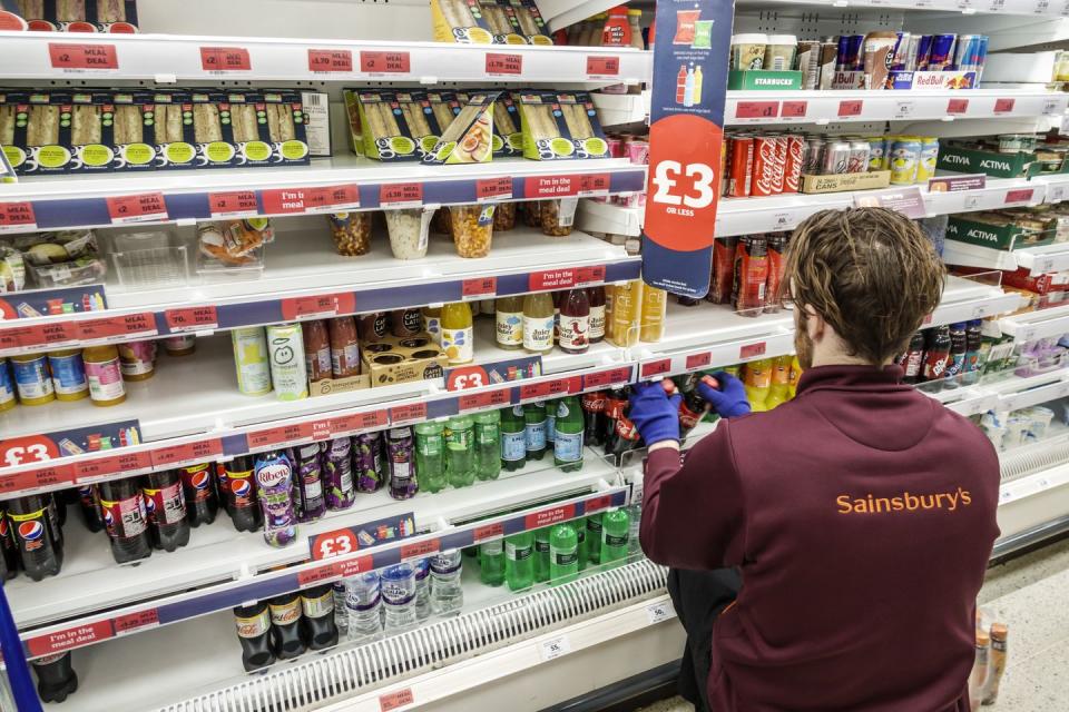 london, sainsburys supermarket, worker stocking refrigerated case