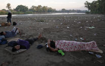 Varios migrantes duermen en la orilla del río Suchiate en Tecún Umán, Guatemala, al otro lado de la frontera con México, el martes 21 de enero de 2020. (AP Foto/Moises Castillo)