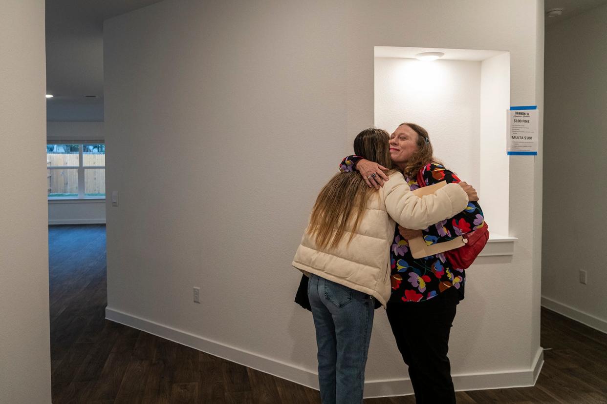 Nidia Gomez hugs JBGoodwin real estate agent Annette Von Ahn at the Gomez family's new home in Hutto.