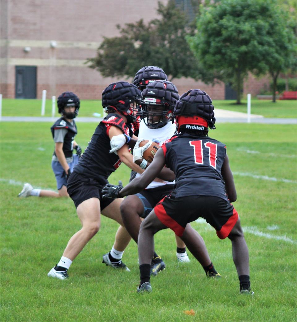 Milan's JJ Woods (center) fights for extra yards on a run during drills on the opening day of football practice Monday, August 7, 2023.