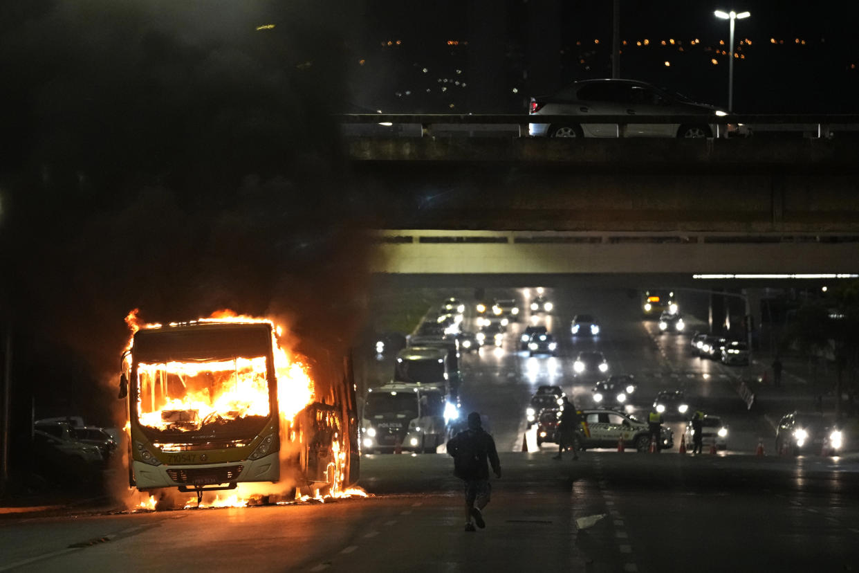 FILE - Supporters of Brazilian President Jair Bolsonaro clash with police setting fire to several vehicles and allegedly trying to storm the headquarters of the Federal Police in Brasilia, Brazil, Dec. 12, 2022. Since Bolsonaro lost re-election to Luiz Inácio Lula da Silva on Oct. 30, his supporters have gathered across the country refusing to concede defeat and asking for the armed forces to intervene. (AP Photo/Eraldo Peres)