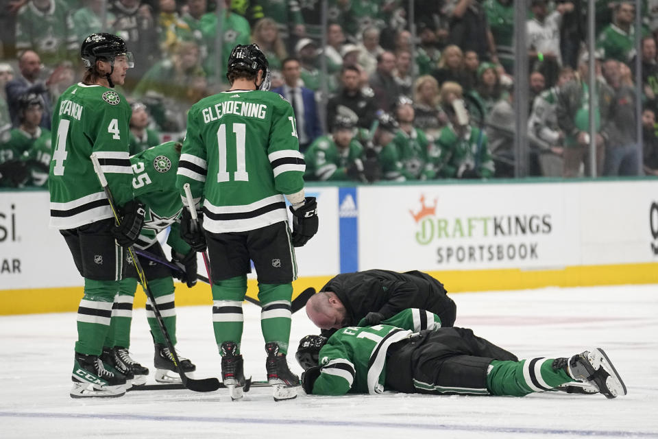 Dallas Stars' Miro Heiskanen (4), Joel Kiviranta (25) and Luke Glendening and staff member check on Radek Faksa, who lies on the ice after colliding with Minnesota Wild's Marcus Foligno during the first period of Game 5 of an NHL hockey Stanley Cup first-round playoff series Tuesday, April 25, 2023, in Dallas. (AP Photo/Tony Gutierrez)