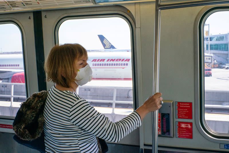 FILE PHOTO: A woman wears a face mask as she rides the air train to reach her terminal at the John F. Kennedy International Airport in New York