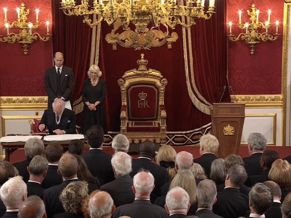 Charles signed the proclamation with William and Camilla looking on.